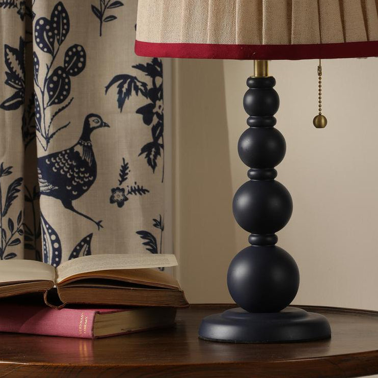 Joules Harewood table lamp in matt blue with a pleated linen shade on a wooden table with books