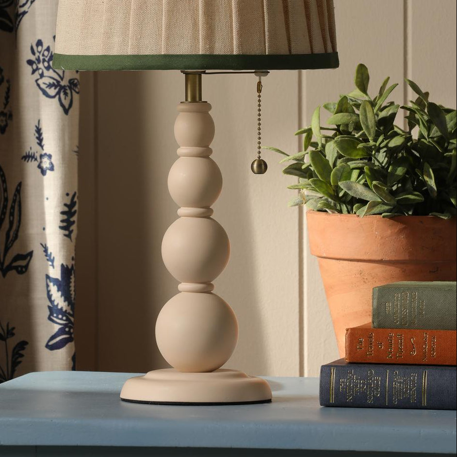Joules Harewood table lamp in matt cream with a pleated linen shade on a blue surface