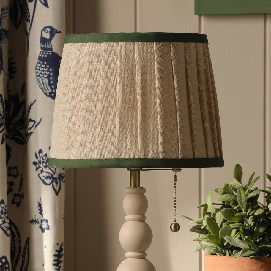 Joules Harewood table lamp with a matt cream base and a pleated linen shade with green trim