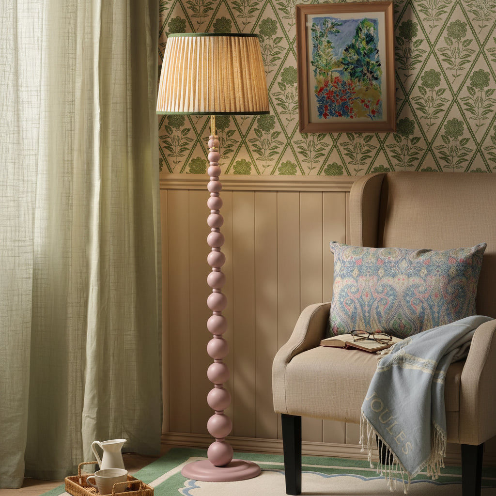 Pink beaded floor lamp with pleated shade next to a beige armchair