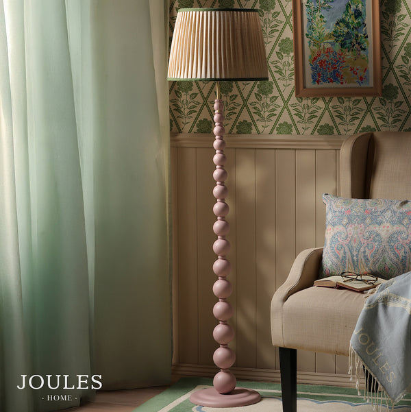 Joules Harewood floor lamp in matt pink with a pleated linen shade standing next to an armchair