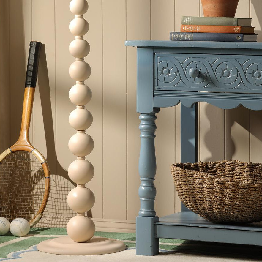 Joules Harewood floor lamp in matt cream with stacked sphere design next to blue wooden console table
