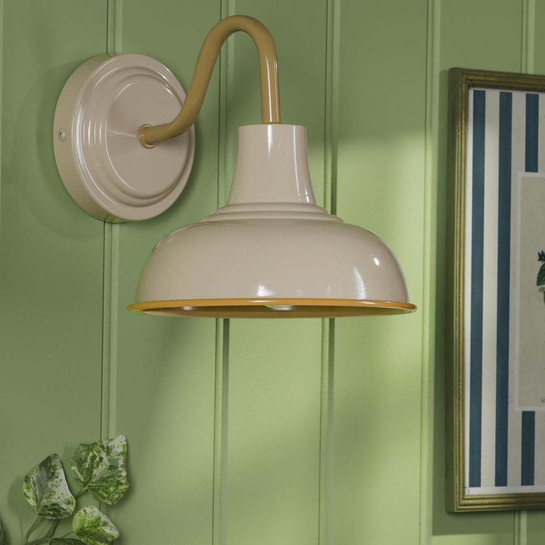 Beige metal gooseneck wall sconce mounted on a green paneled wall