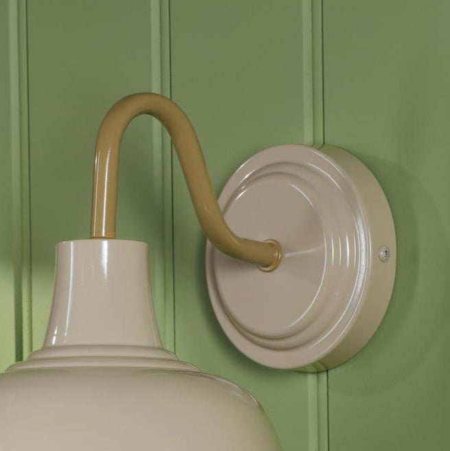 Cream wall sconce with curved arm mounted on green paneled wall