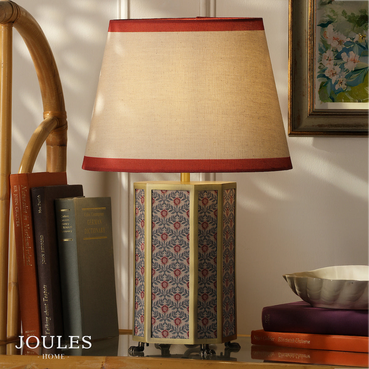 Joules Helmingham table lamp with floral patterned base and red edged linen shade on a table with books