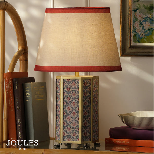 Joules Helmingham table lamp with floral patterned base and red edged linen shade on a table with books