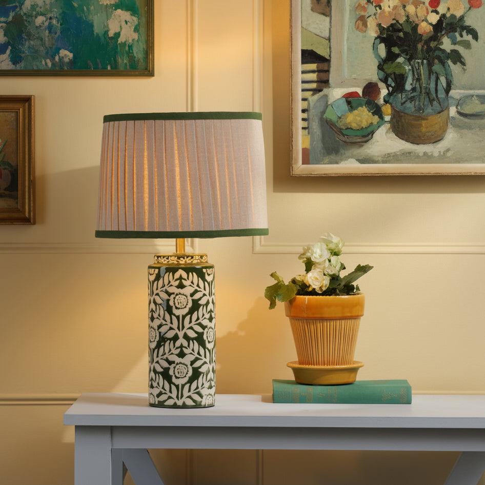 Joules Highclere ceramic table lamp in green with a pleated linen shade on a table