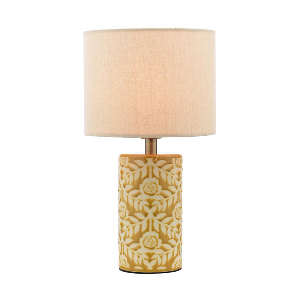Table lamp with a cylindrical mustard yellow ceramic base featuring a white floral pattern and a beige fabric drum shade