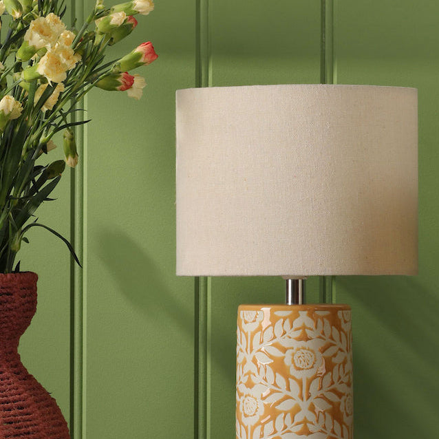 Joules Highclere yellow ceramic table lamp with cream linen shade next to flowers