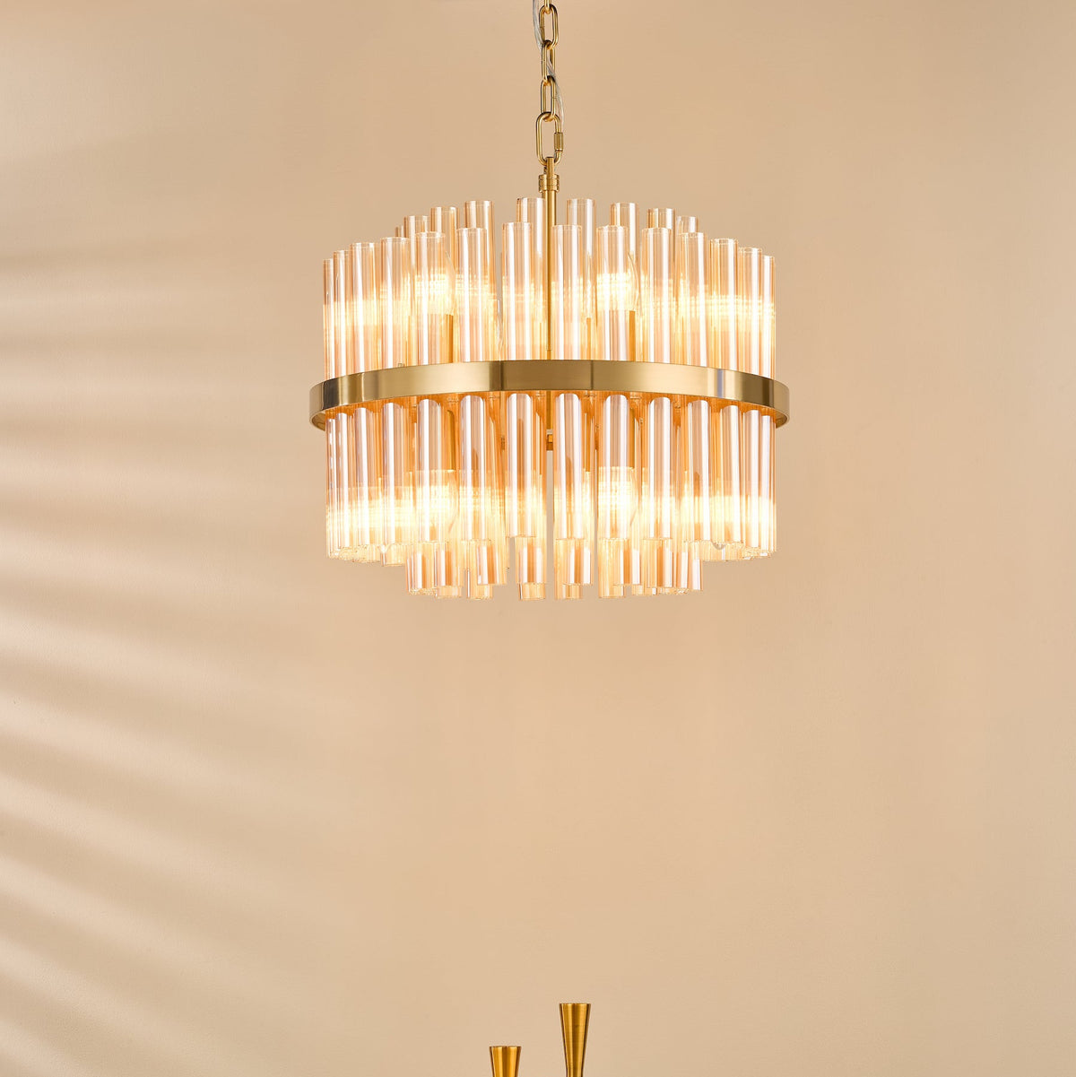 Round chandelier with two tiers of amber glass rods and a gold frame