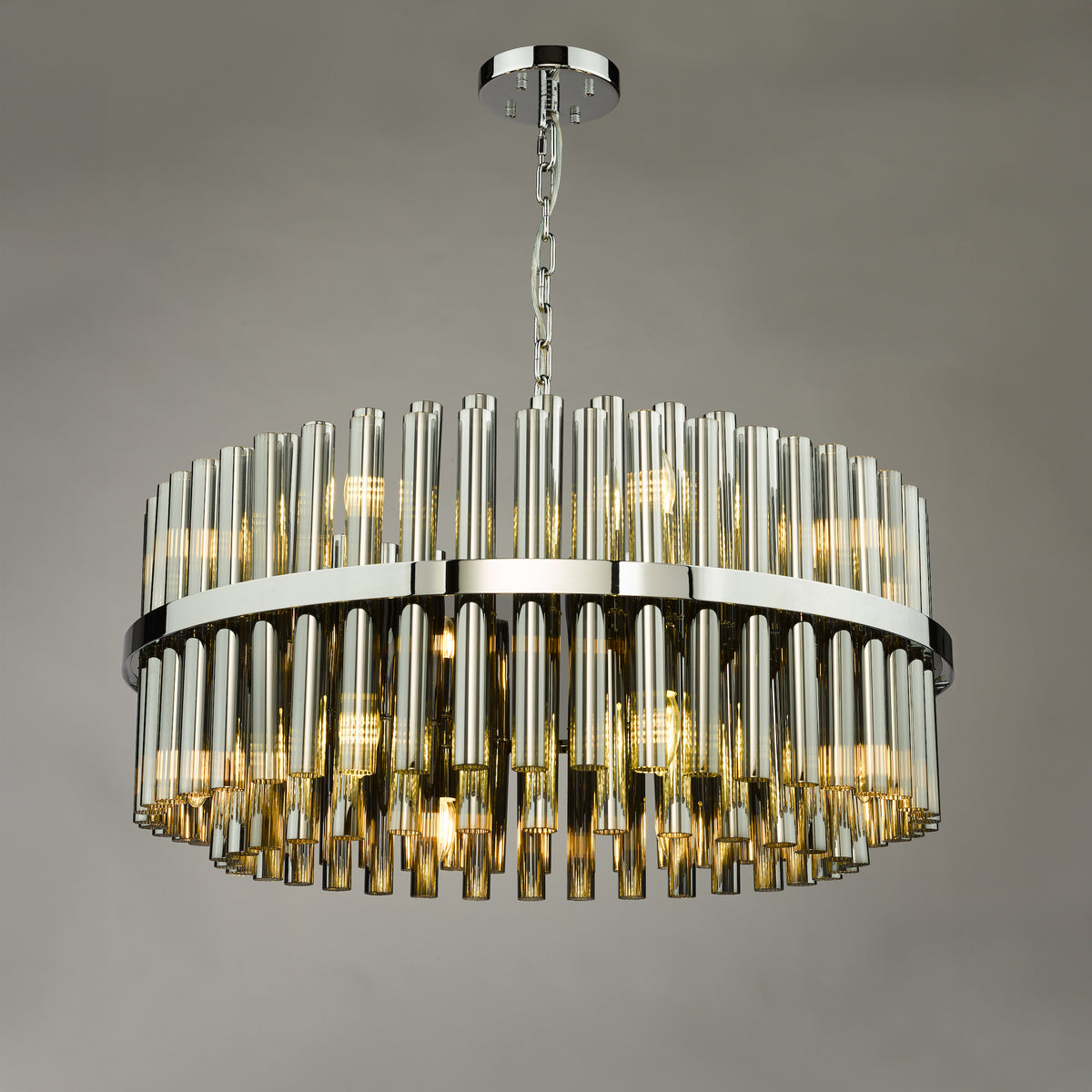 Round chandelier with chrome frame and clear glass rods, illuminated with warm light