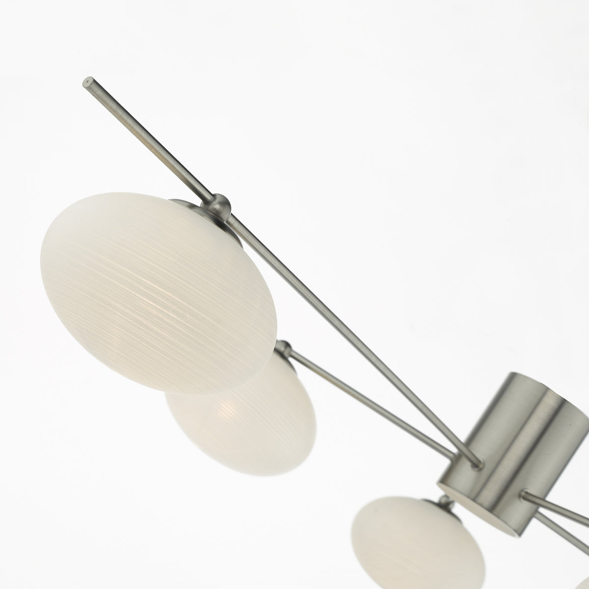 Close-up of a modern chandelier with white oval shades and brushed metal arms.