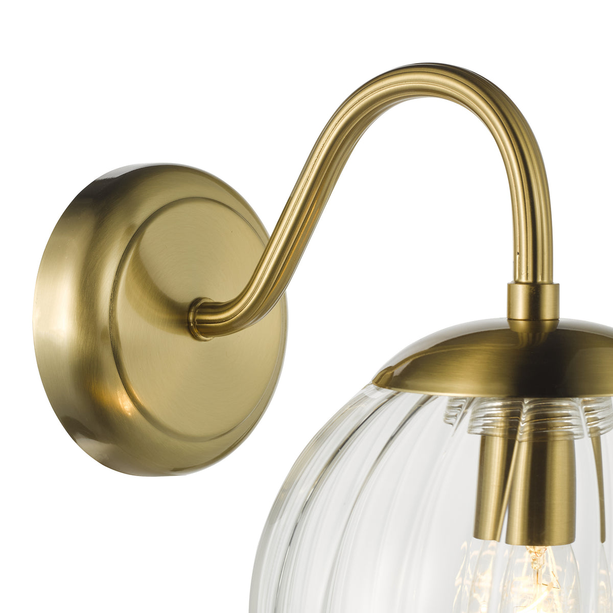 Close up of a brass wall light with a ribbed glass shade