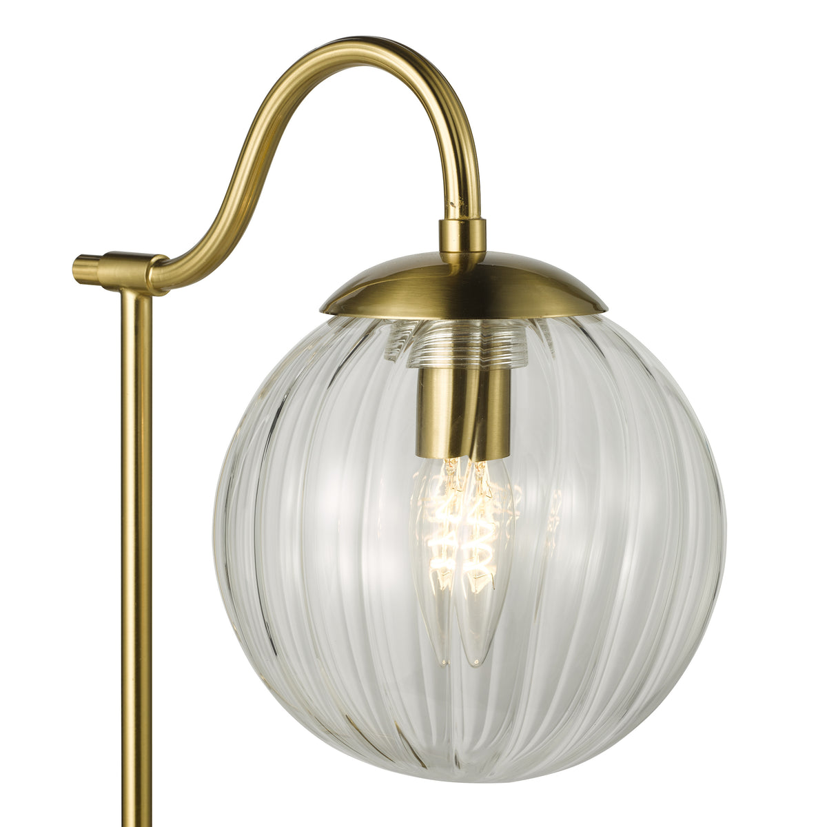 Close up of a brass floor lamp with a ribbed glass globe shade and an exposed filament bulb