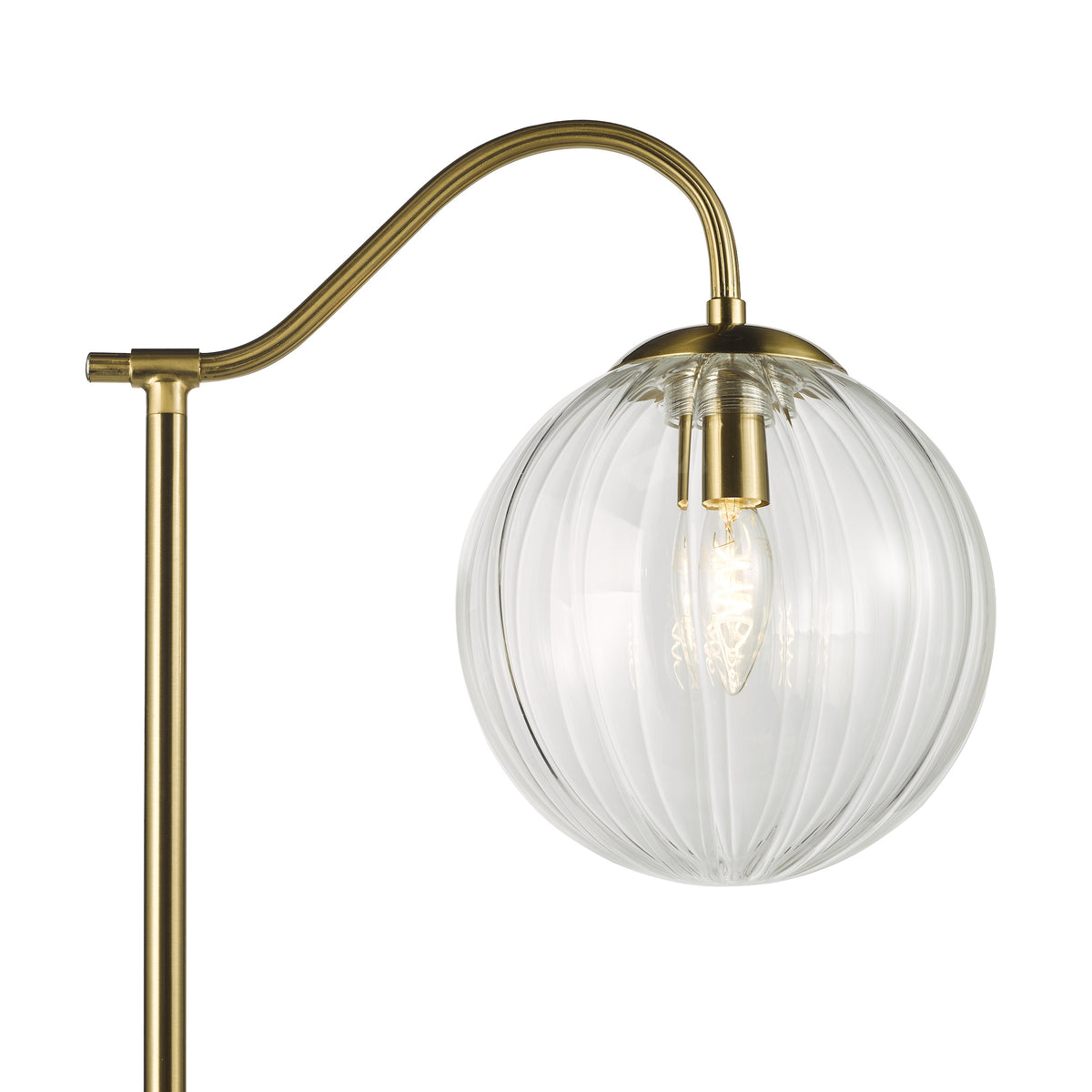 Close up of a brass floor lamp with a ribbed glass globe shade and an exposed bulb
