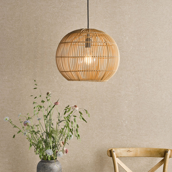 Rattan pendant light with a lit bulb, above a vase of wildflowers and a wooden chair
