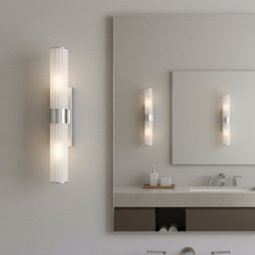 Two vertical wall sconces with ribbed white glass shades and chrome accents, one on a wall and one in a mirror