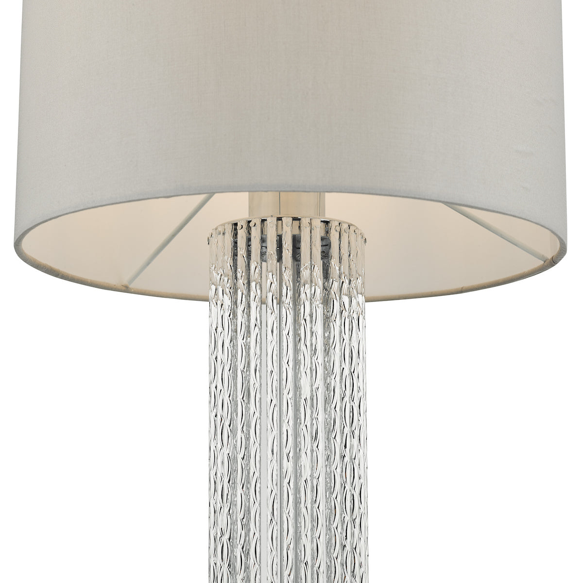 Close-up of a table lamp with a textured glass base and a light gray fabric shade.