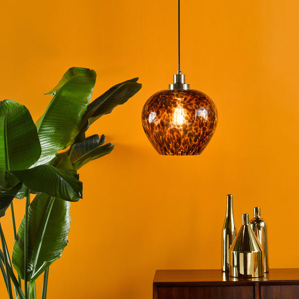 A brown glass pendant light with a textured pattern hangs in front of an orange wall.