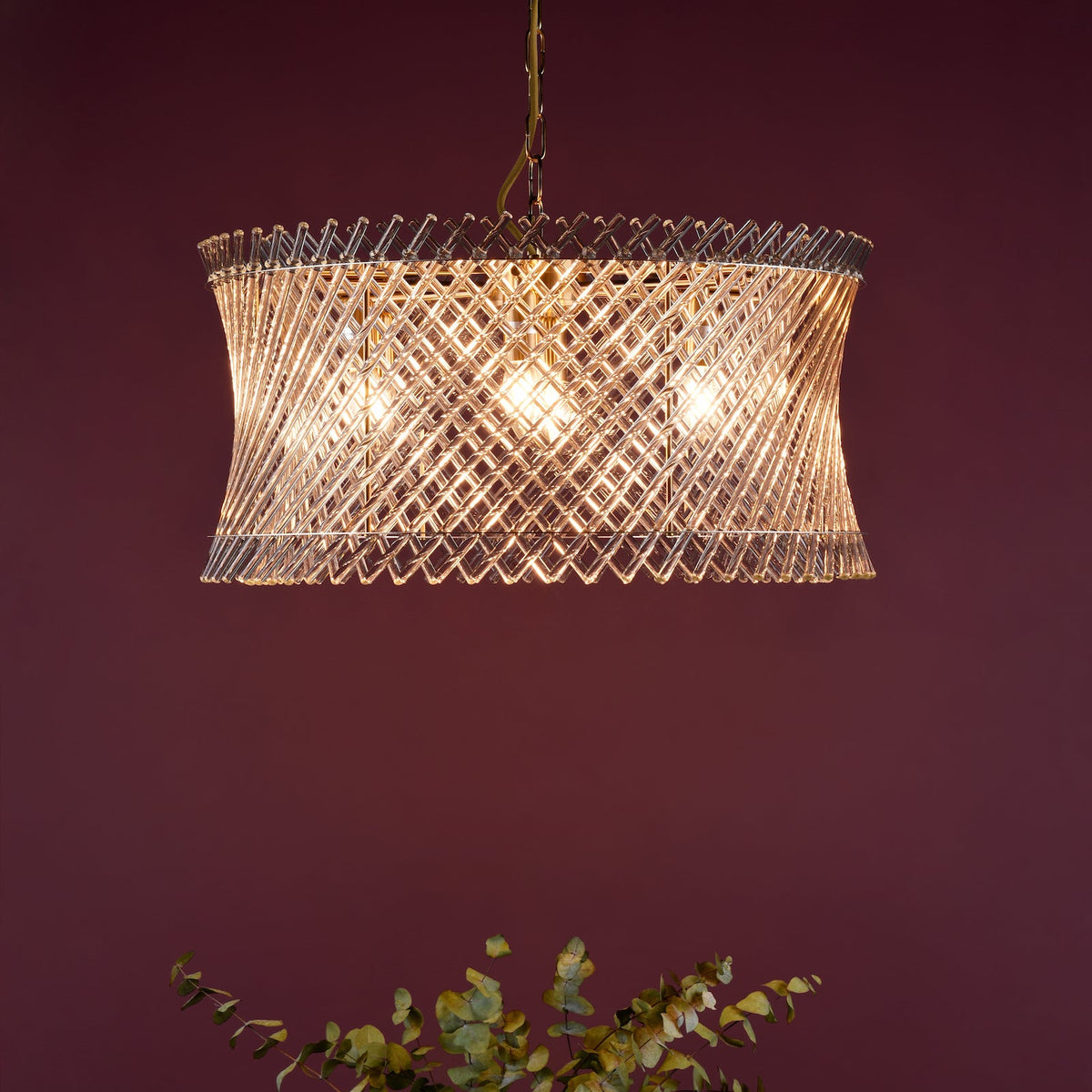 Rectangular glass chandelier with a twisted, textured pattern and three visible bulbs, against a dark red wall