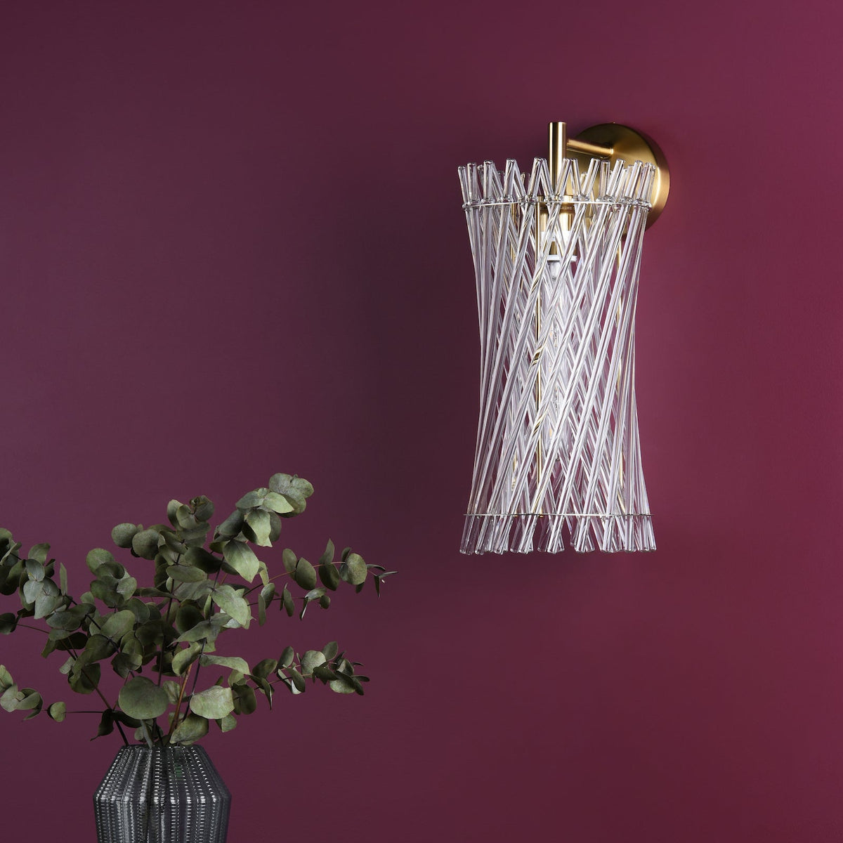 Gold and glass wall sconce with a plant in a vase on a purple wall