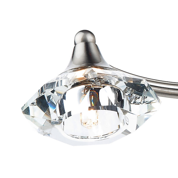 Close-up of a crystal light fixture with a brushed metal base and a clear, faceted shade.