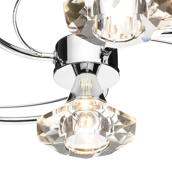Close-up of a modern chrome light fixture with faceted crystal shades.