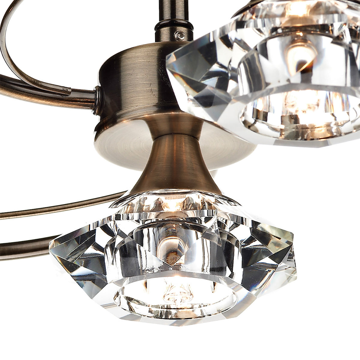 Close-up of a bronze light fixture with faceted crystal shades and glowing bulbs.