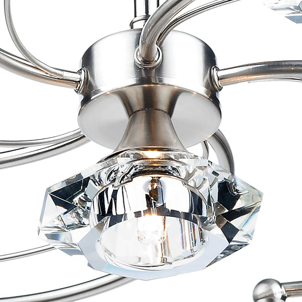Close-up of a brushed nickel light fixture with a faceted crystal shade and glowing bulb.
