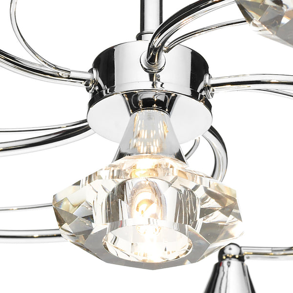 Close-up of a chrome chandelier with clear faceted crystal shades and illuminated bulbs.