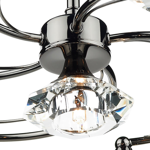 Close-up of a chrome chandelier with a faceted crystal shade and an illuminated bulb.