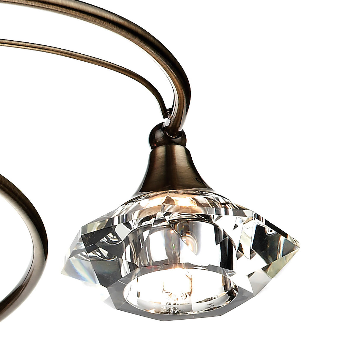 Close-up of a bronze light fixture with a faceted crystal shade, glowing with warm light.