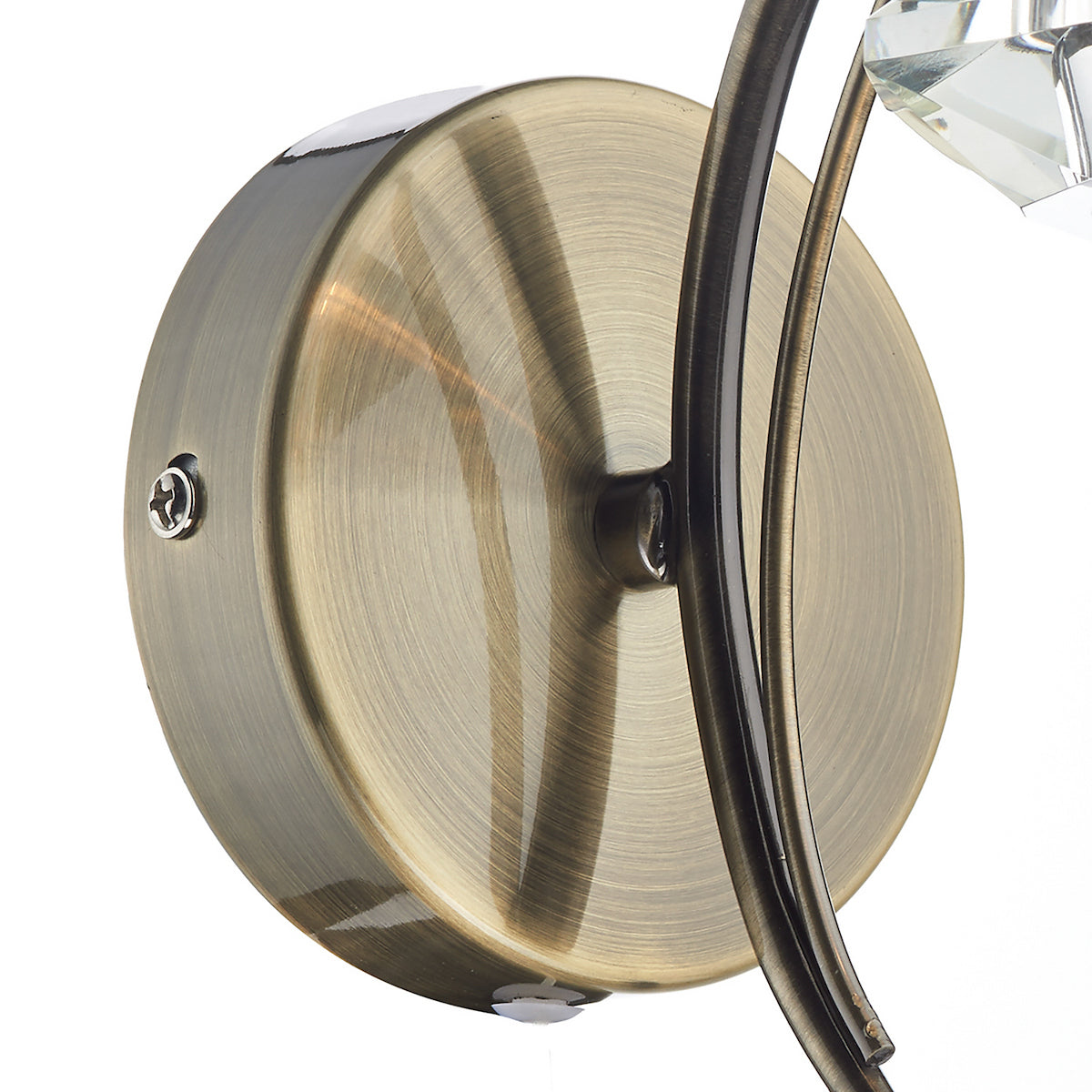 Close-up of a brass wall sconce base with a curved arm and crystal accent.