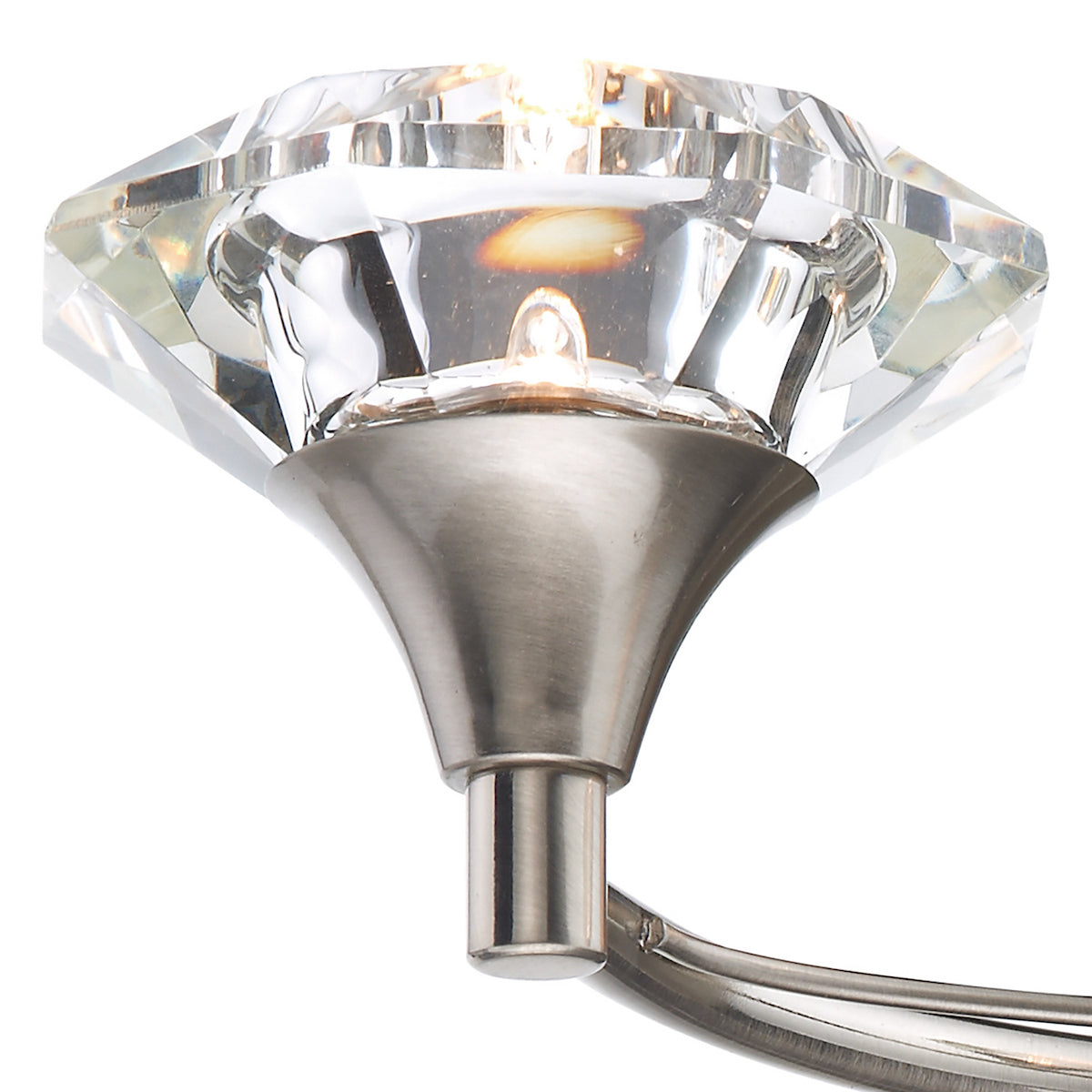 Close-up of a crystal light fixture with a brushed nickel base and a glowing bulb inside.