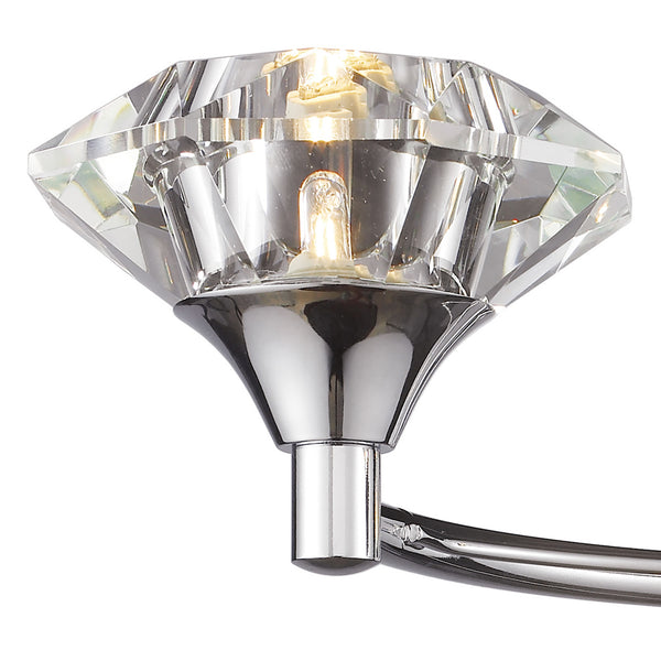 Close-up of a crystal light fixture with a chrome base and a glowing bulb inside.