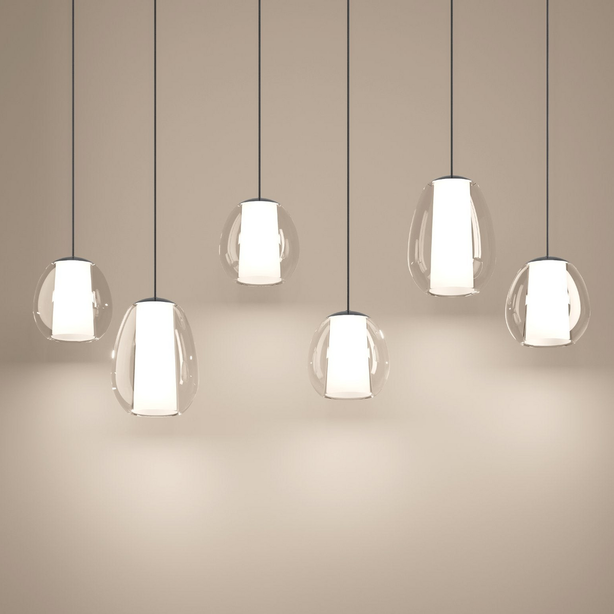 Six clear glass pendant lights with white inner shades hanging against a light brown wall
