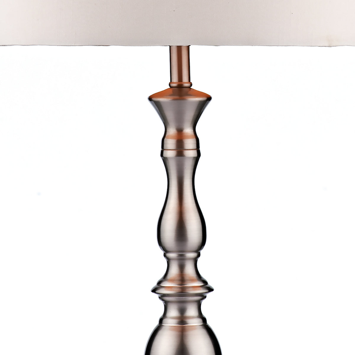 Close-up of a brushed nickel lamp base with a white fabric shade.