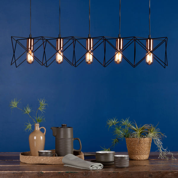 Geometric black metal chandelier with six Edison bulbs over a rustic wooden table with plants and pottery.