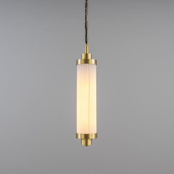 Cylindrical pendant light with a fluted frosted glass shade and brass hardware hanging from a chain