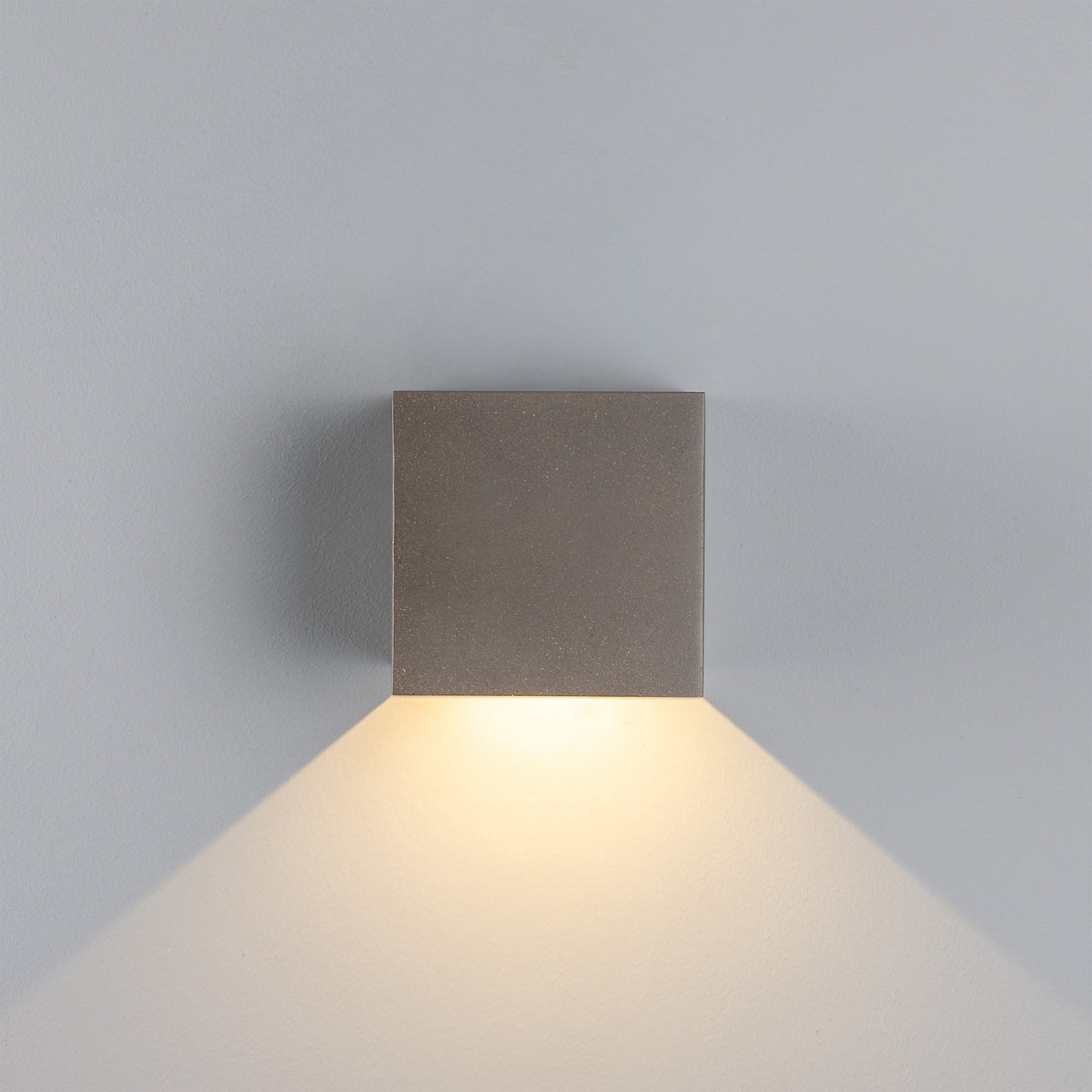 Mullan Marseille concrete LED wall light with downward light beam on a grey wall