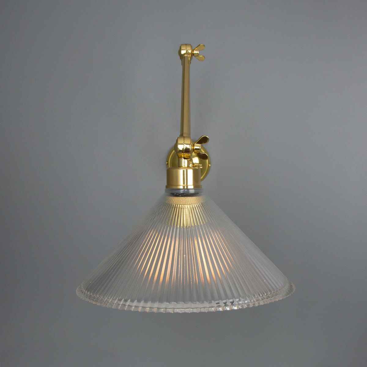 Brass wall sconce with a ribbed glass cone shade