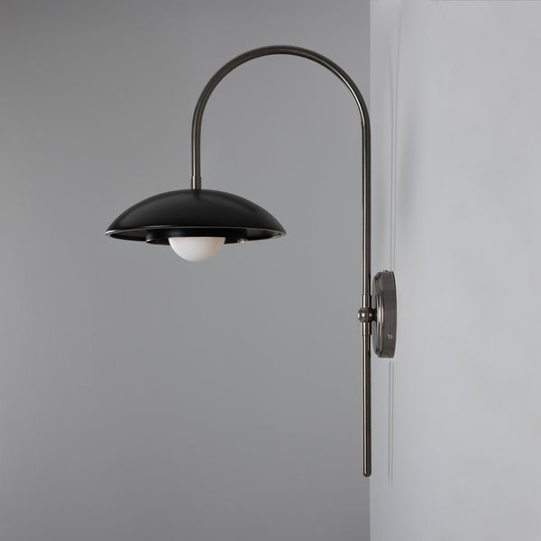 Black metal wall sconce with a curved arm and a white globe bulb