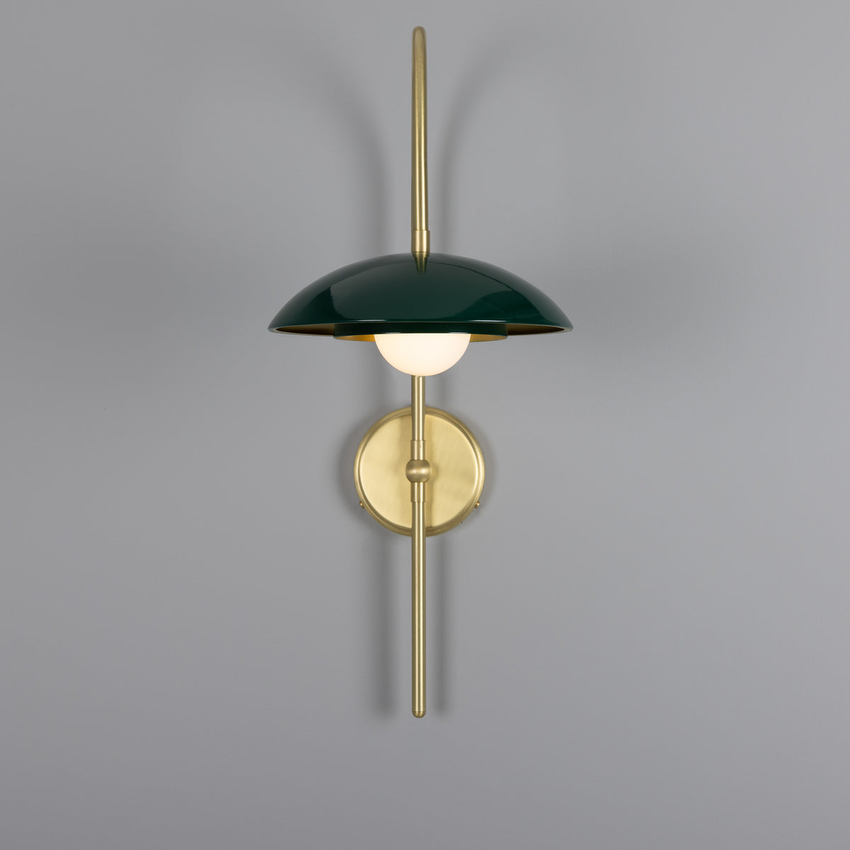 Mullan Marrakesh Art Deco arc wall light in satin brass and racing green with a central glowing globe bulb