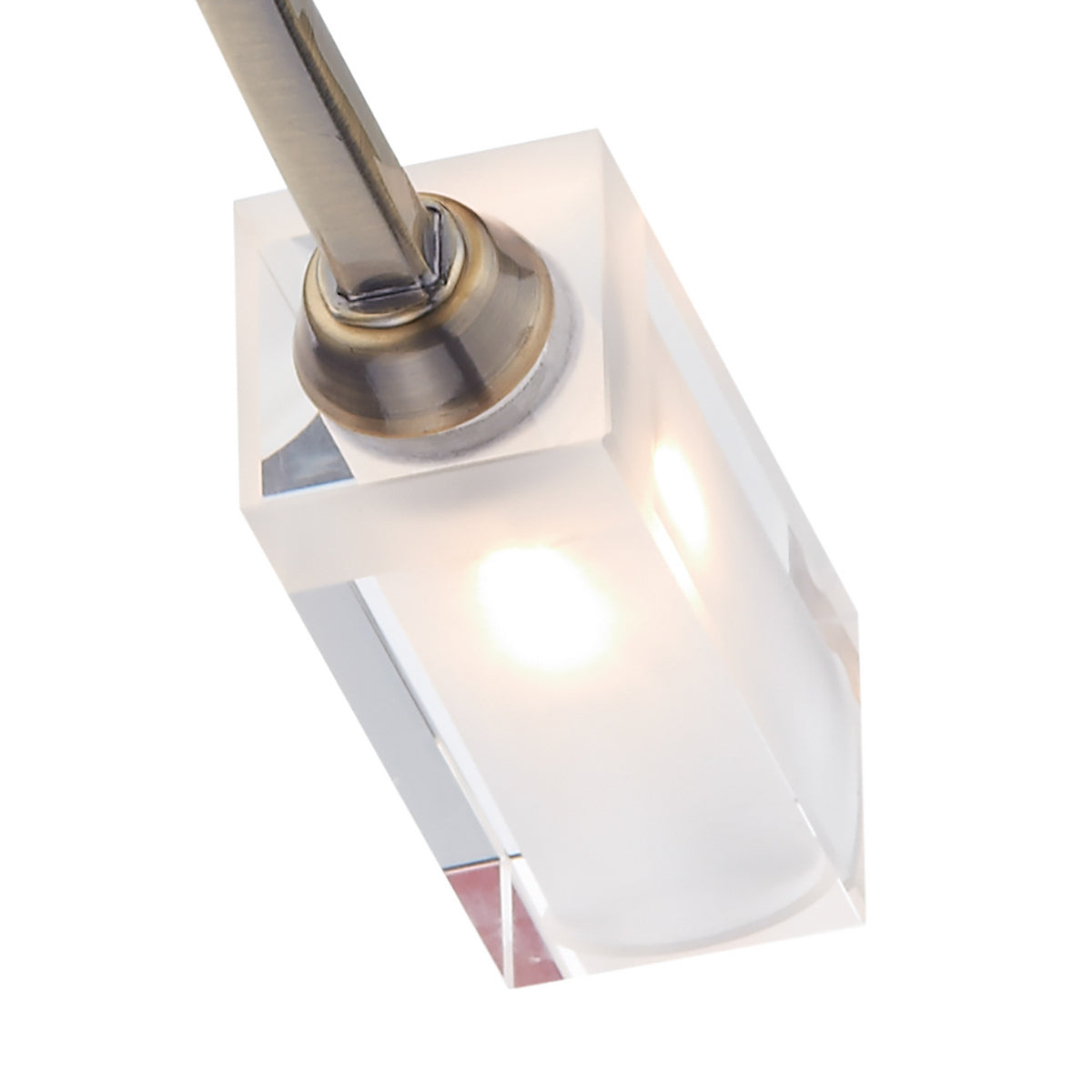 Close-up of a clear crystal light fixture with a brushed brass accent and a glowing bulb.
