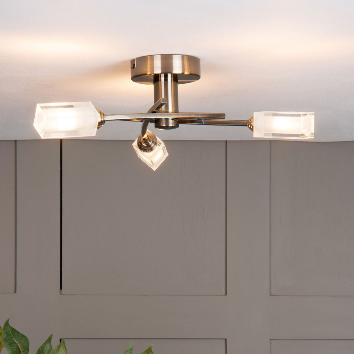 Brushed brass ceiling light with three clear, rectangular crystal shades, one pointing down.