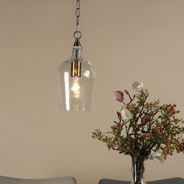 Clear glass pendant light with a gold bulb holder and a bouquet of flowers.