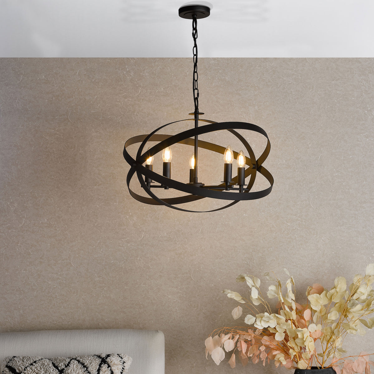 Black metal chandelier with five exposed bulbs and an orb-shaped frame