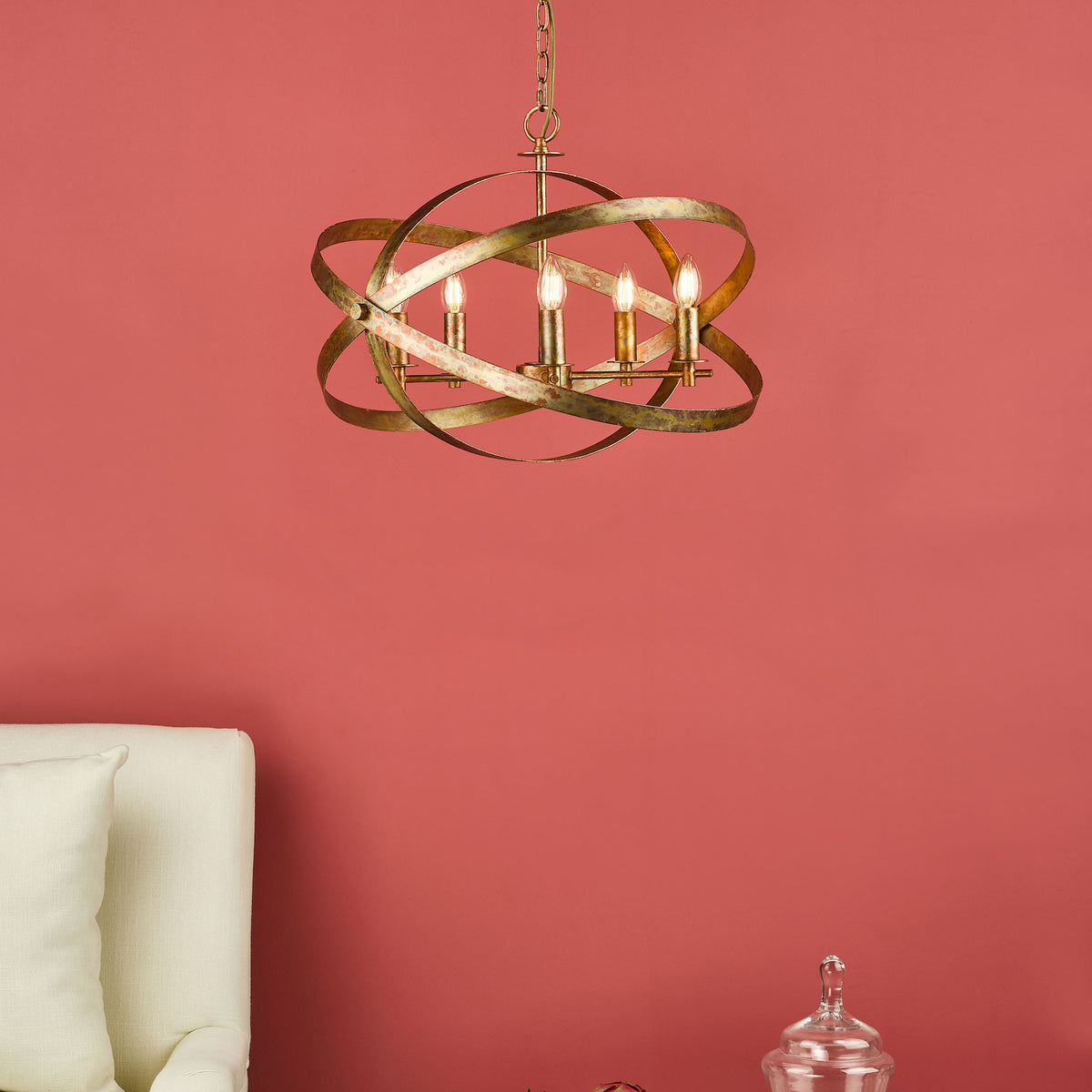 A gold chandelier with four lights hangs from the ceiling against a coral wall