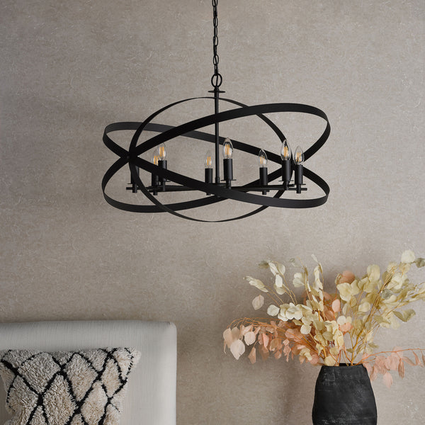 Black metal chandelier with six exposed bulbs, featuring an orb design, hanging above a white sofa and dried flowers.