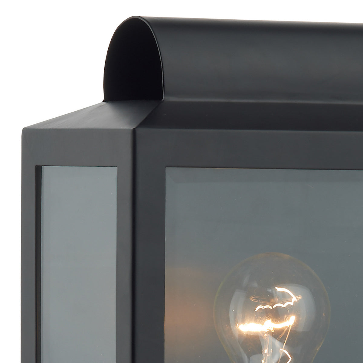 Close-up of a black outdoor lantern with a glowing light bulb inside.